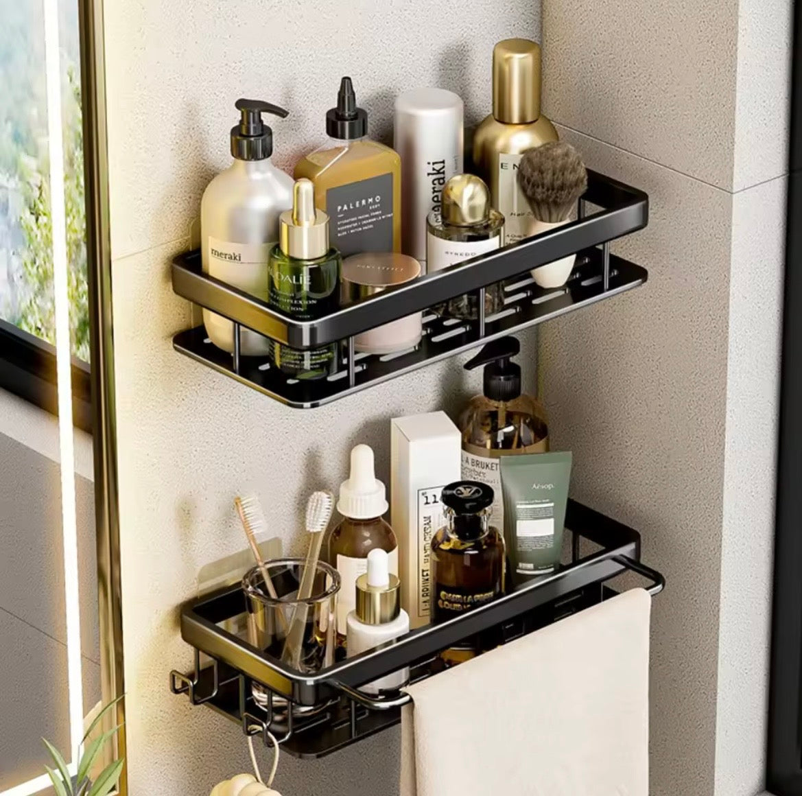 Two black adhesive bathroom shelves holding toiletries beside a mirror